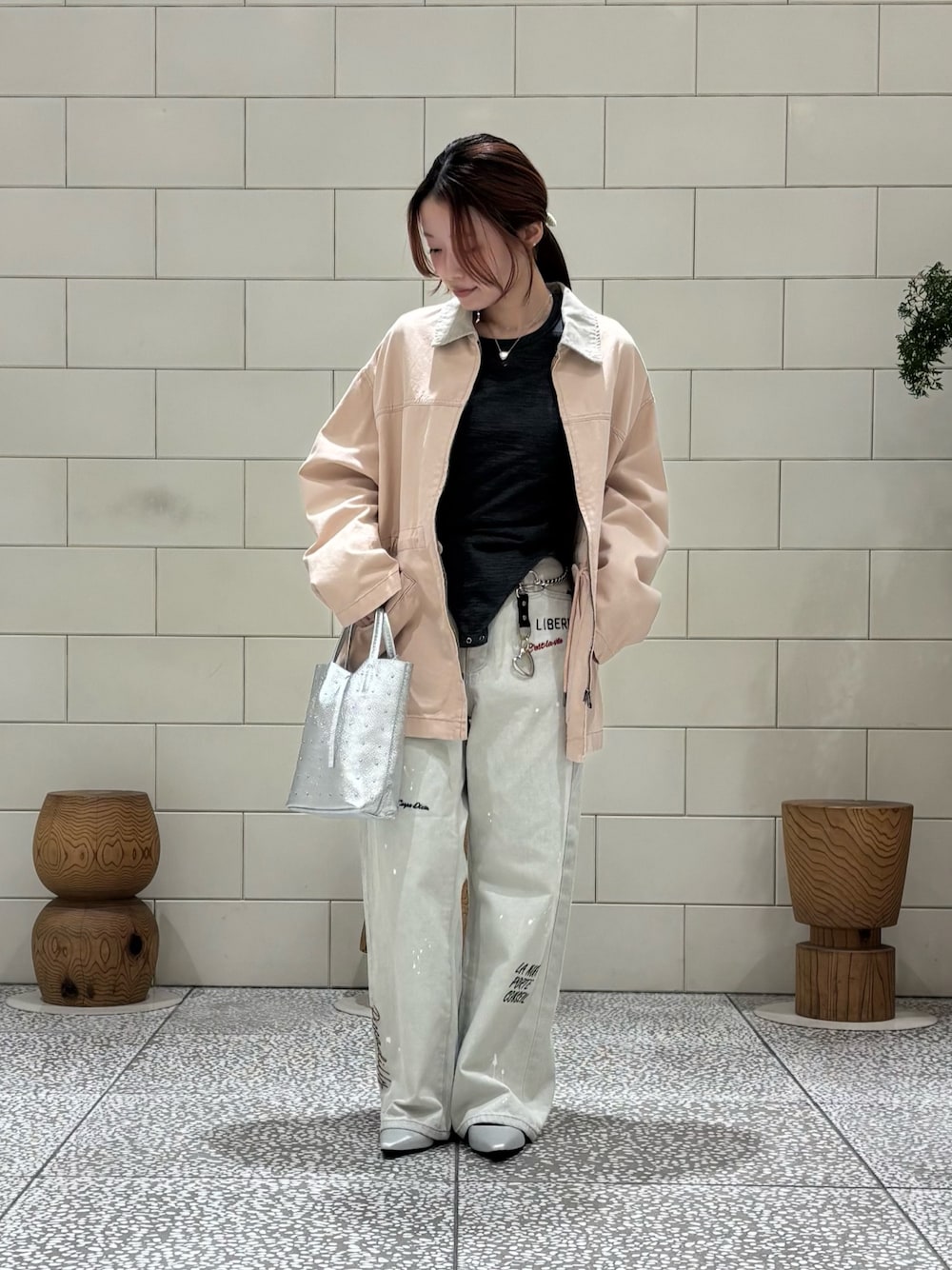 ピンク系のカバーオール、シルバー系のトートバッグ、グレー系のデニムパンツを着用したレディースの冬コーディネートの1枚目の写真