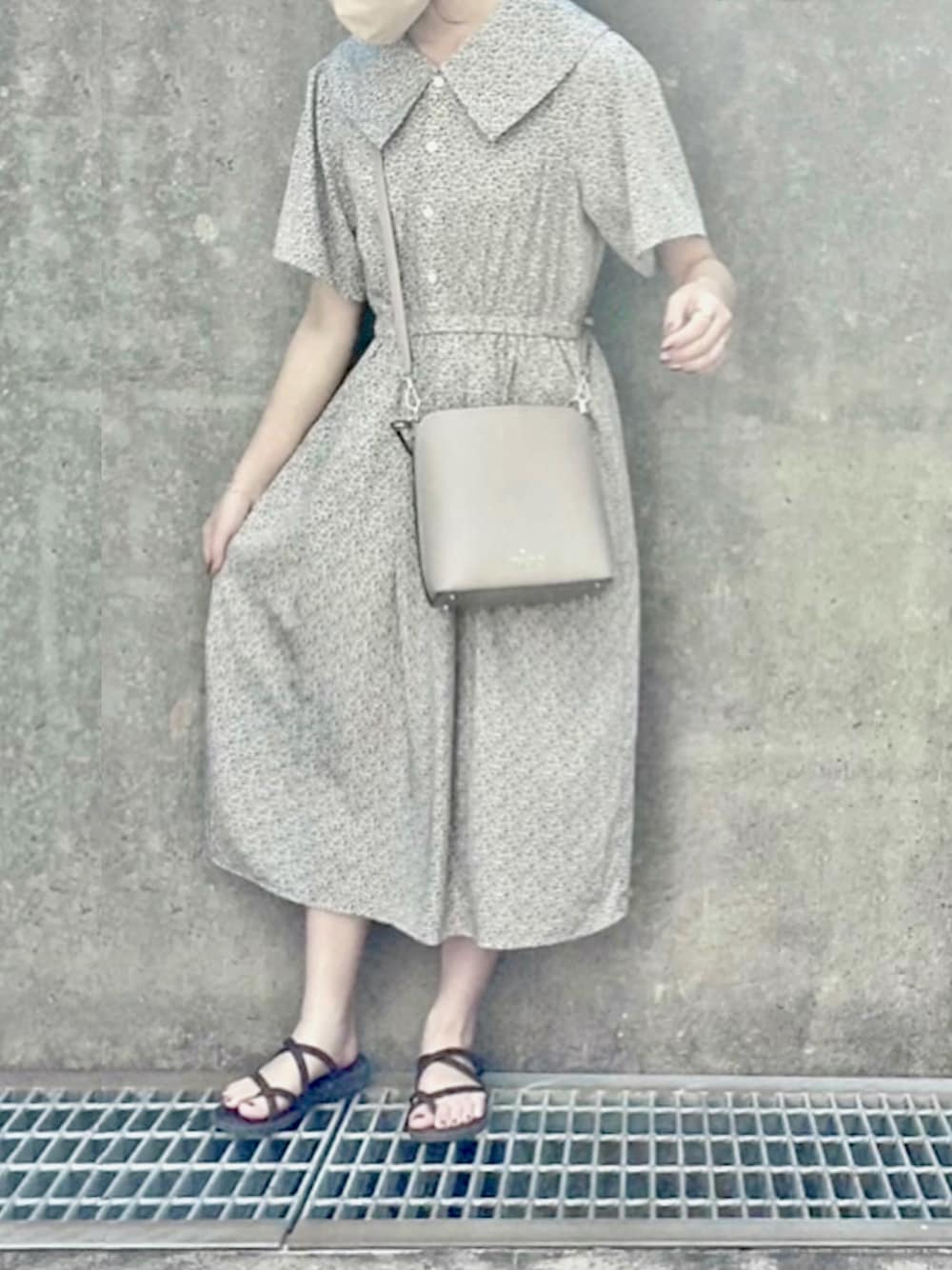 ホワイト系のワンピース、ベージュ系のハンドバッグ、ブラウン系のサンダルを着用したレディースの夏コーディネートの1枚目の写真