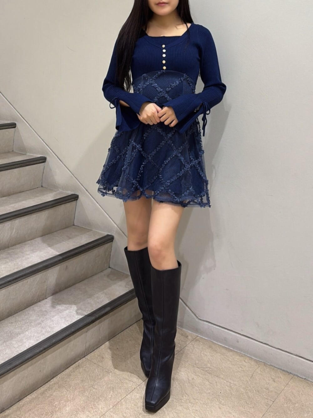 ブルー系のワンピース、ブラック系のブーツを着用したレディースの秋コーディネートの1枚目の写真