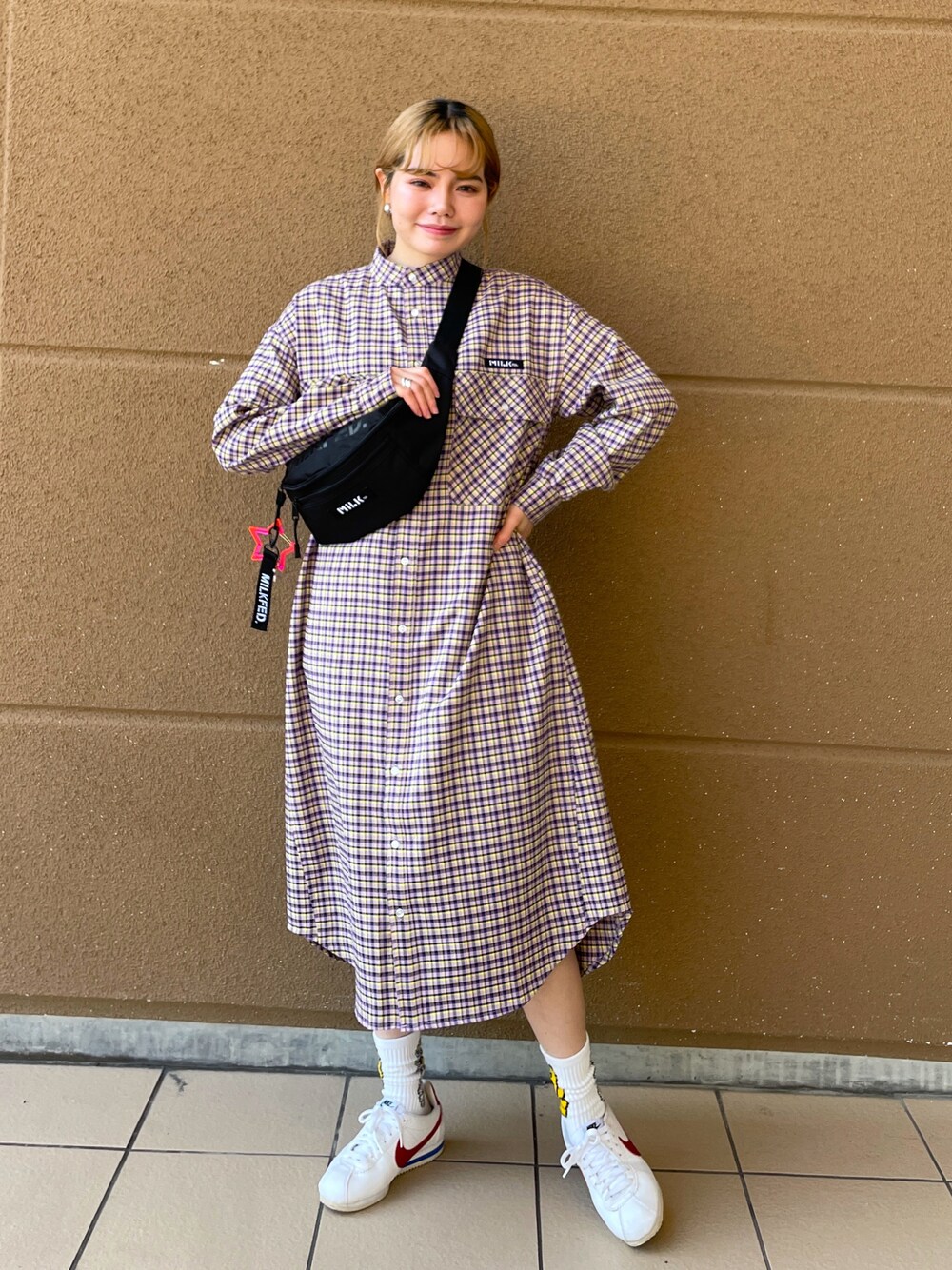 パープル系のワンピース、レッド系のボディバッグ/ウエストポーチを着用したレディースの冬コーディネートの1枚目の写真