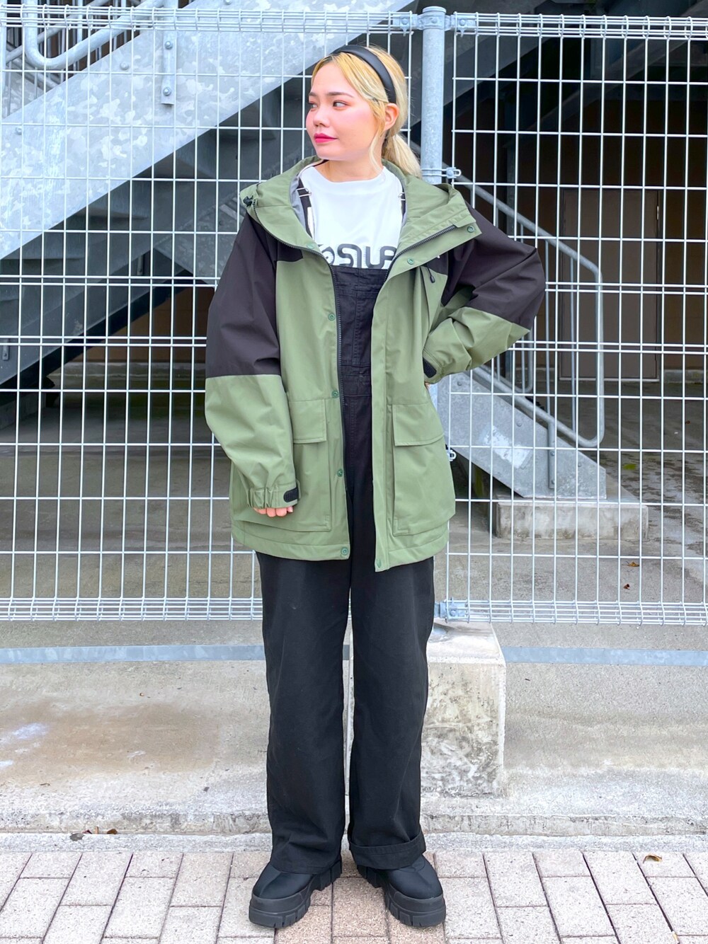 グリーン系のマウンテンパーカー、ホワイト系のサロペット/オーバーオール、ホワイト系のTシャツ/カットソーを着用したレディースの秋コーディネートの1枚目の写真
