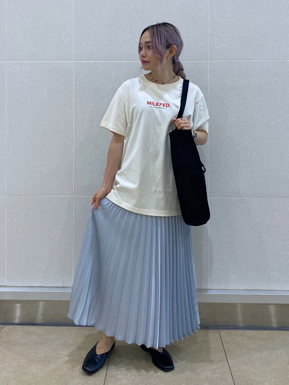 グレー系のスカート、ベージュ系のTシャツ/カットソー、ブラック系のトートバッグを着用したレディースの夏コーディネートの1枚目の写真