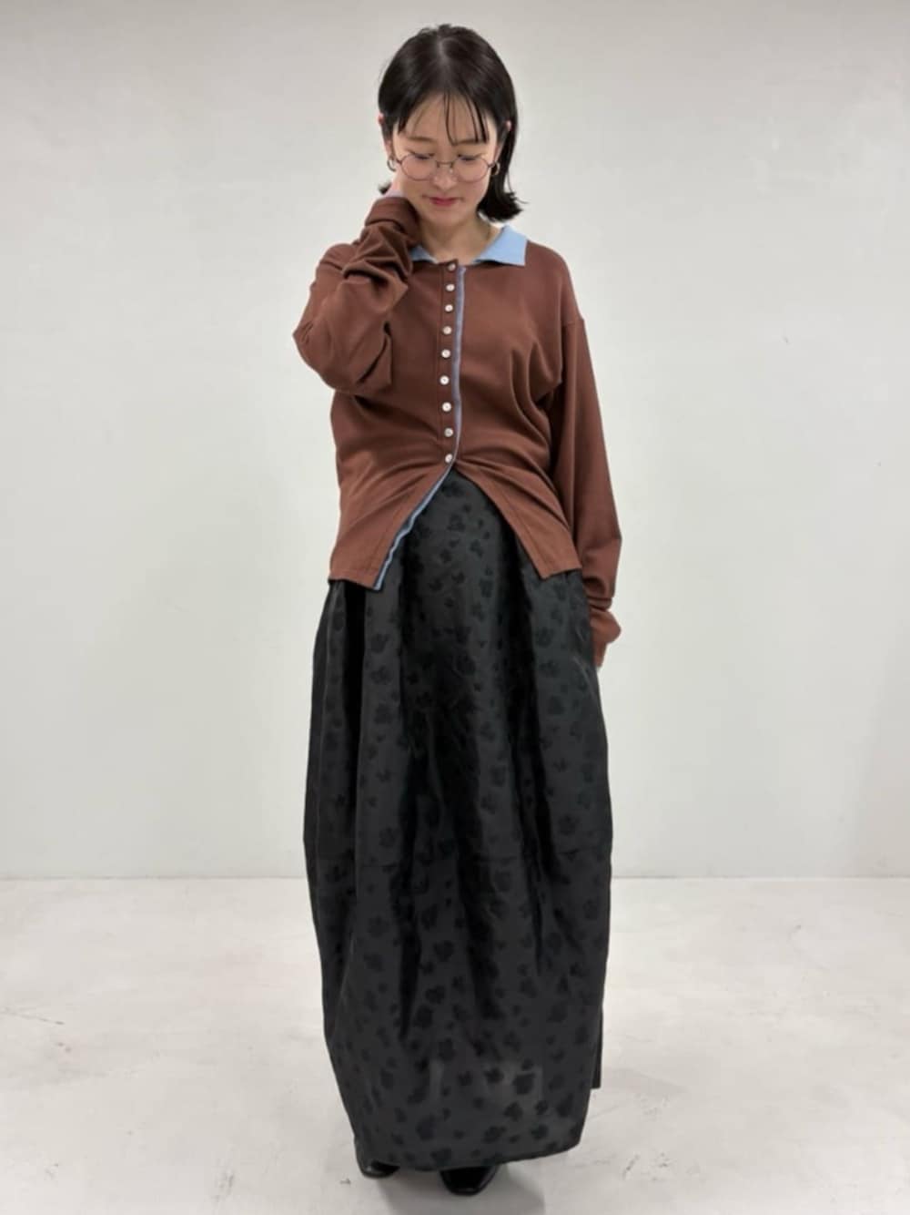 ブラウン系のカーディガン/ボレロ、ブラック系のスカートを着用したレディースの冬コーディネートの1枚目の写真