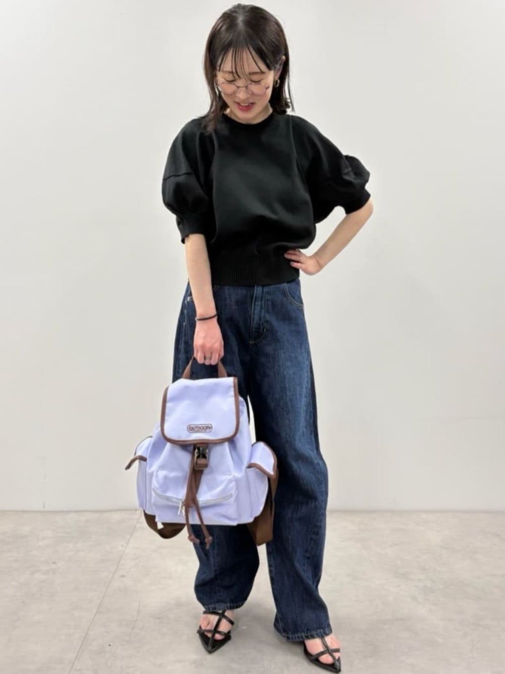 ブルー系のデニムパンツ、ブラック系のニット/セーター、パープル系のバックパック/リュックを着用したレディースの春コーディネートの1枚目の写真