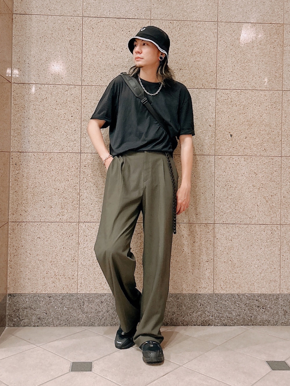グリーン系のパンツ、ブラック系のTシャツ/カットソー、ブラック系のショルダーバッグを着用したメンズの夏コーディネートの1枚目の写真