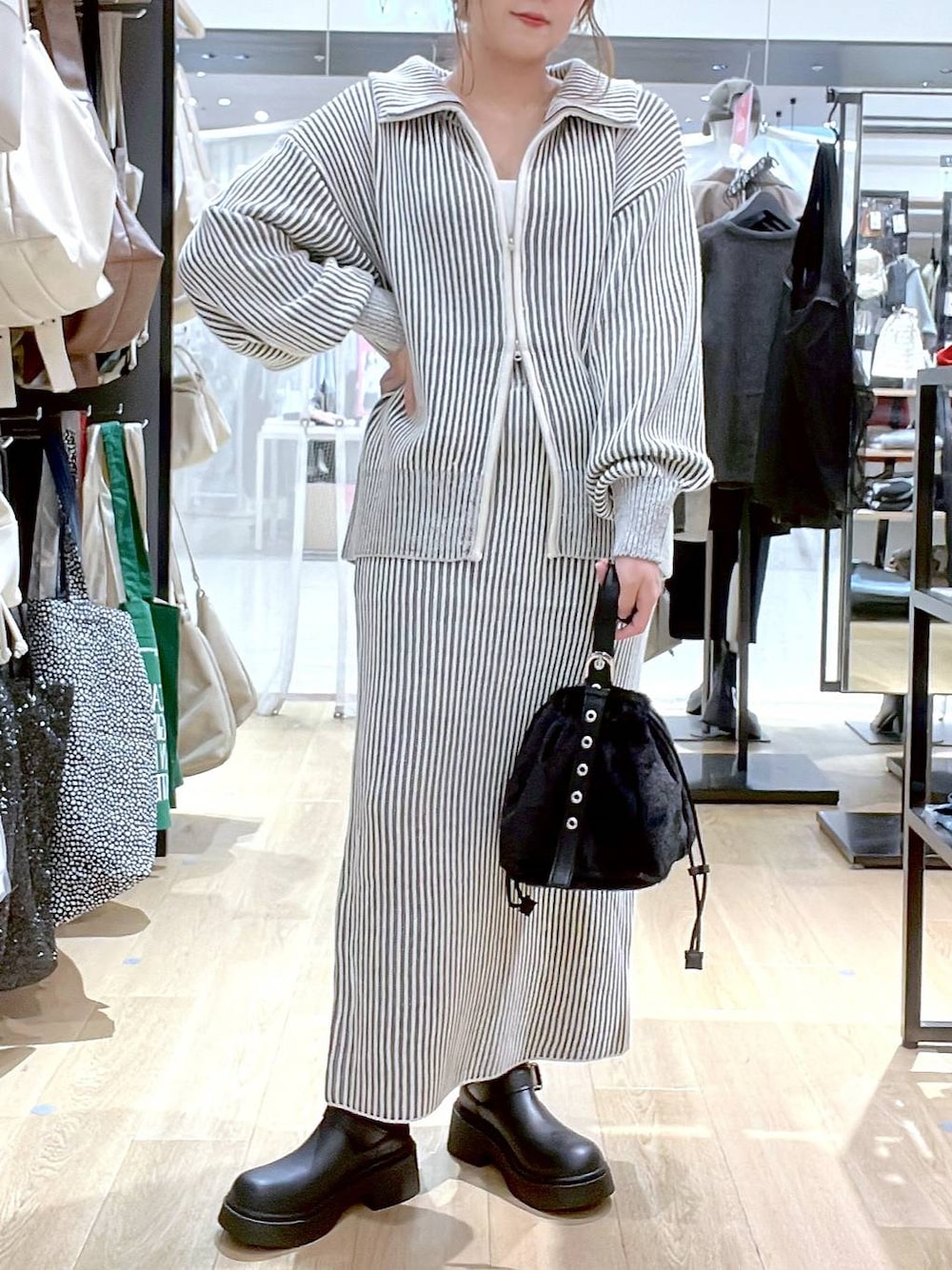 ホワイト系のタンクトップ、ブラック系のハンドバッグ、ベージュ系のスカートを着用したレディースの秋コーディネートの1枚目の写真