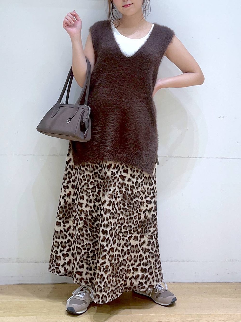 ホワイト系のタンクトップ、ブラウン系のスニーカー、ブラウン系のベストを着用したレディースの秋コーディネートの1枚目の写真