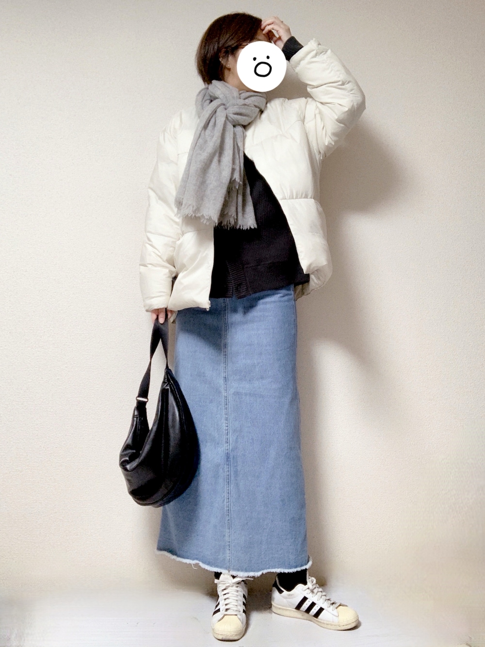 ホワイト系のスニーカー、ブラック系のショルダーバッグ、ブルー系のデニムスカートを着用したレディースの冬コーディネートの1枚目の写真