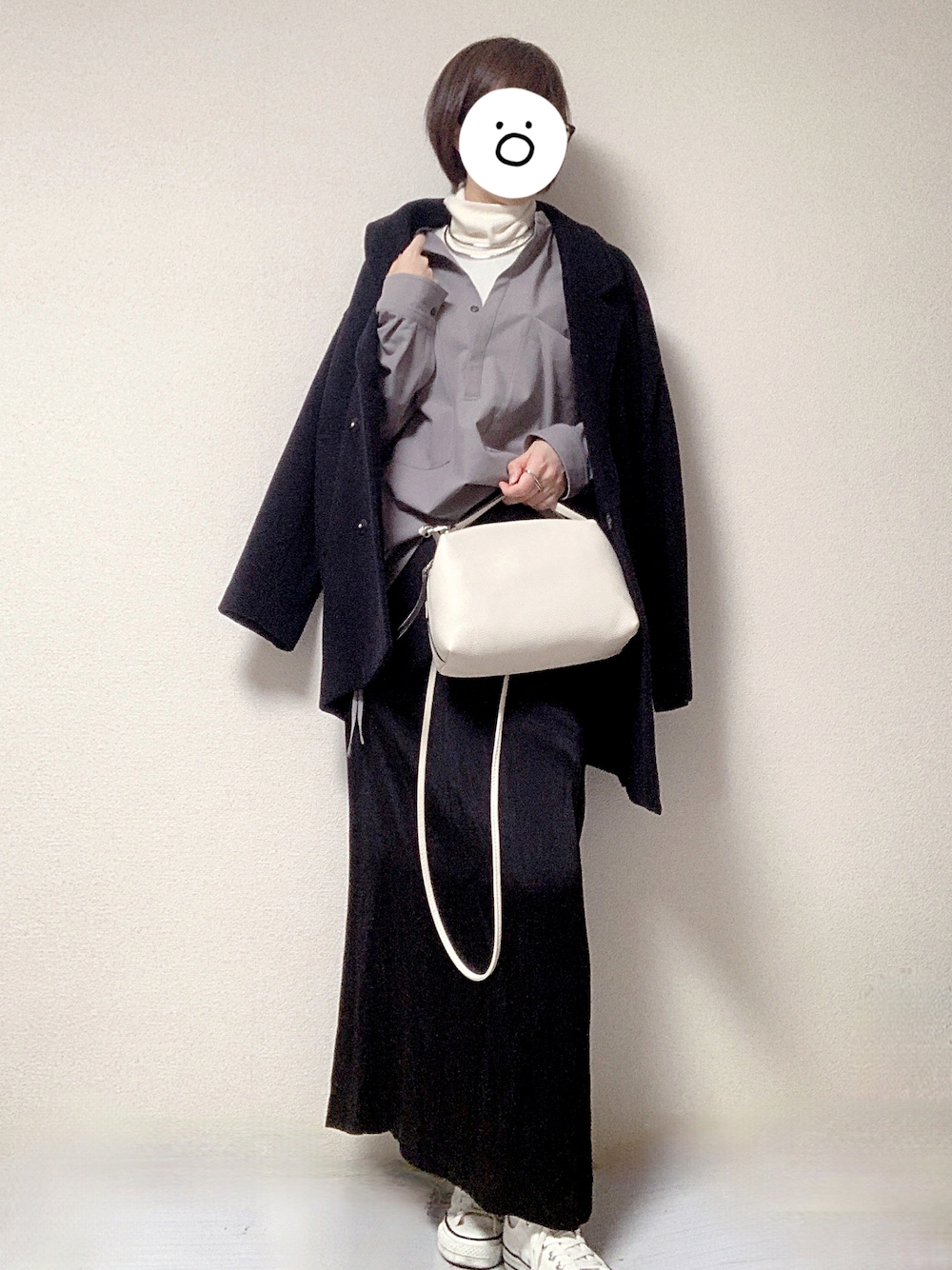 ホワイト系のスニーカー、ブラック系のスカート、ホワイト系のショルダーバッグを着用したレディースの冬コーディネートの1枚目の写真