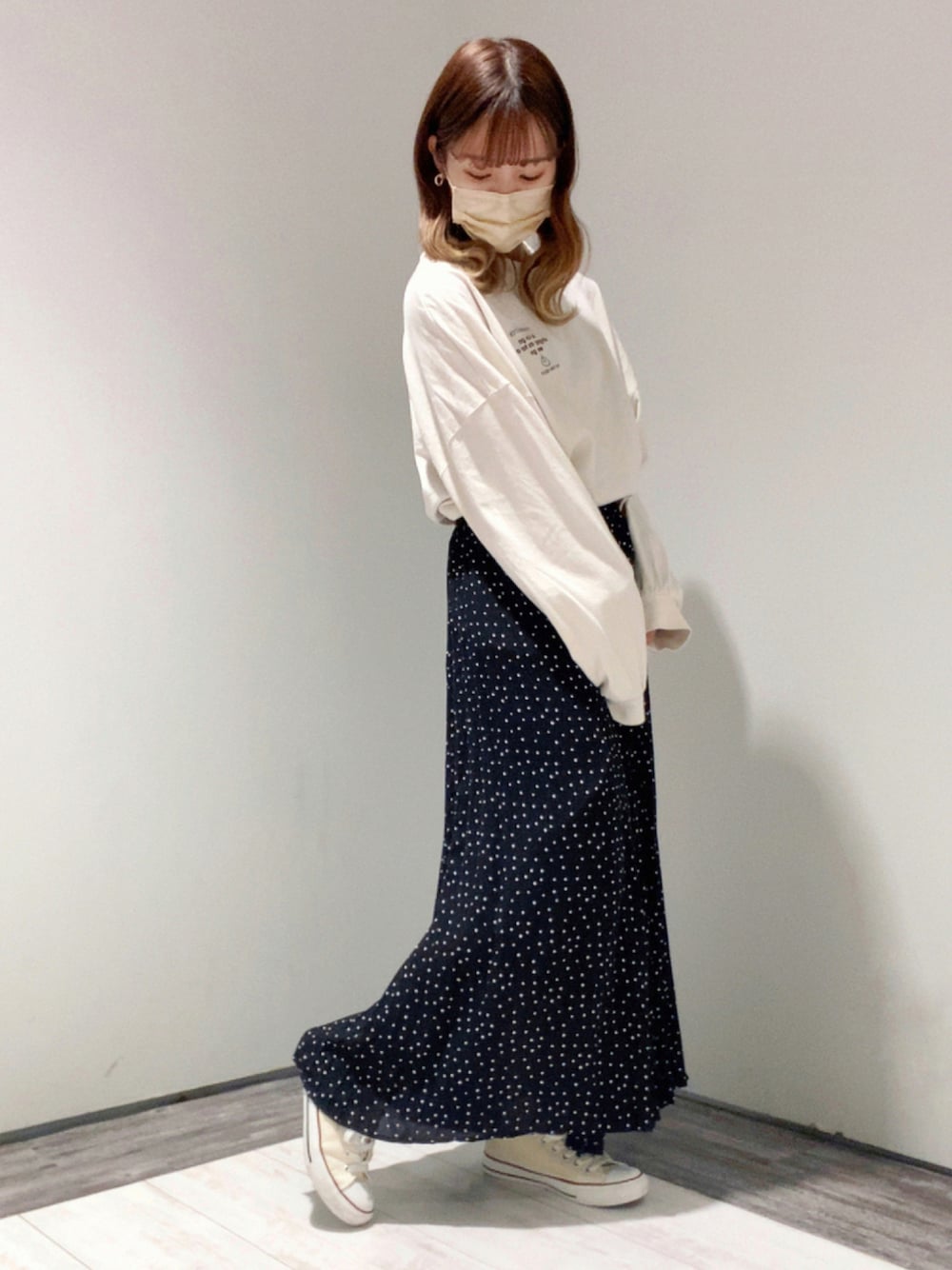 ブラック系のスカート、ホワイト系のTシャツ/カットソー、ホワイト系のスニーカーを着用したレディースの秋コーディネートの1枚目の写真