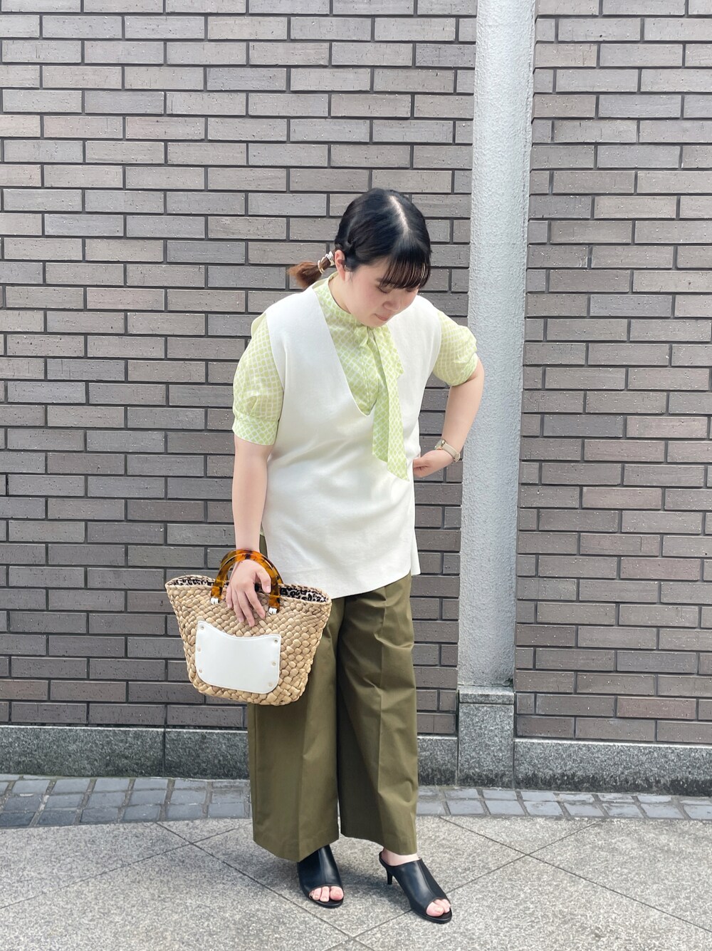 ホワイト系のベスト、イエロー系のシャツ/ブラウス、ホワイト系のハンドバッグを着用したレディースの春コーディネートの1枚目の写真