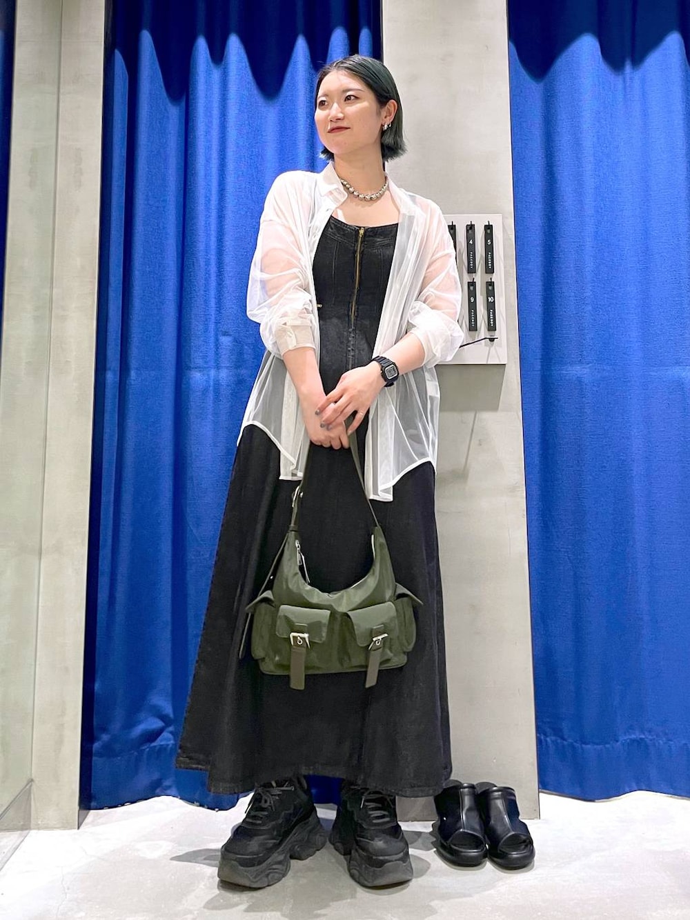 グリーン系のショルダーバッグ、ブラック系のスニーカー、ブラック系のワンピースを着用したレディースの春コーディネートの1枚目の写真