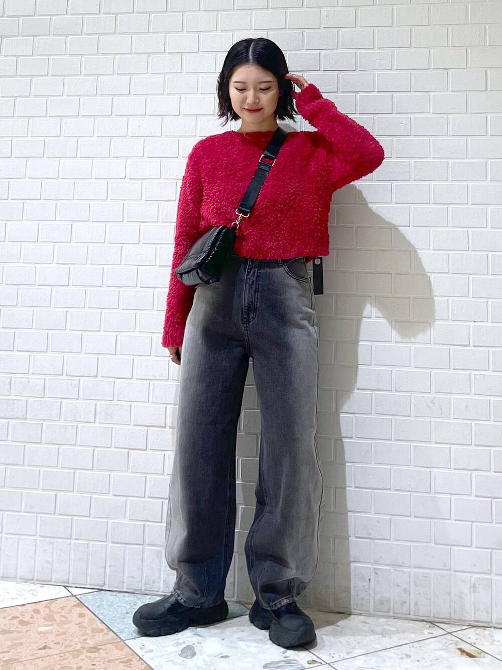 ブラック系のデニムパンツ、ブラック系のブーツ、ブラック系のショルダーバッグを着用したレディースの秋コーディネートの1枚目の写真