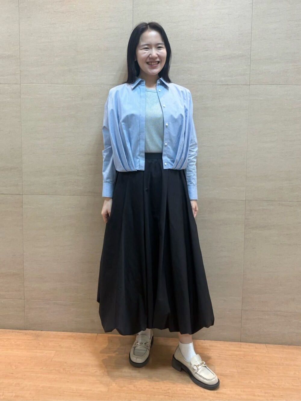 ブラック系のスカート、ブルー系のシャツ/ブラウス、シルバー系のタンクトップを着用したレディースの春コーディネートの1枚目の写真