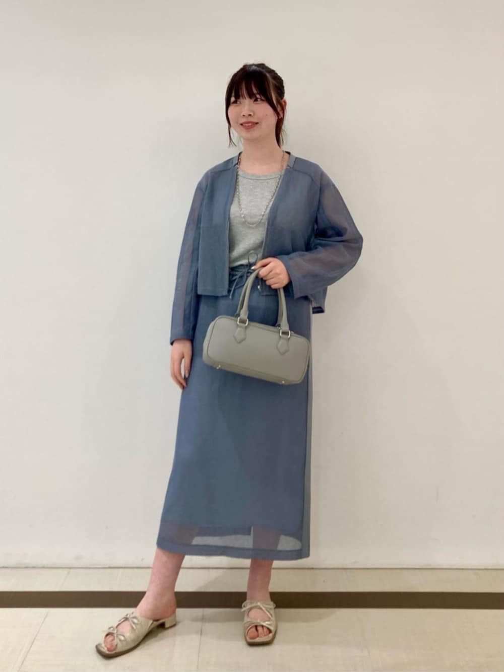 グレー系のボストンバッグ、ブルー系のブルゾン、ブルー系のスカートを着用したレディースの夏コーディネートの1枚目の写真