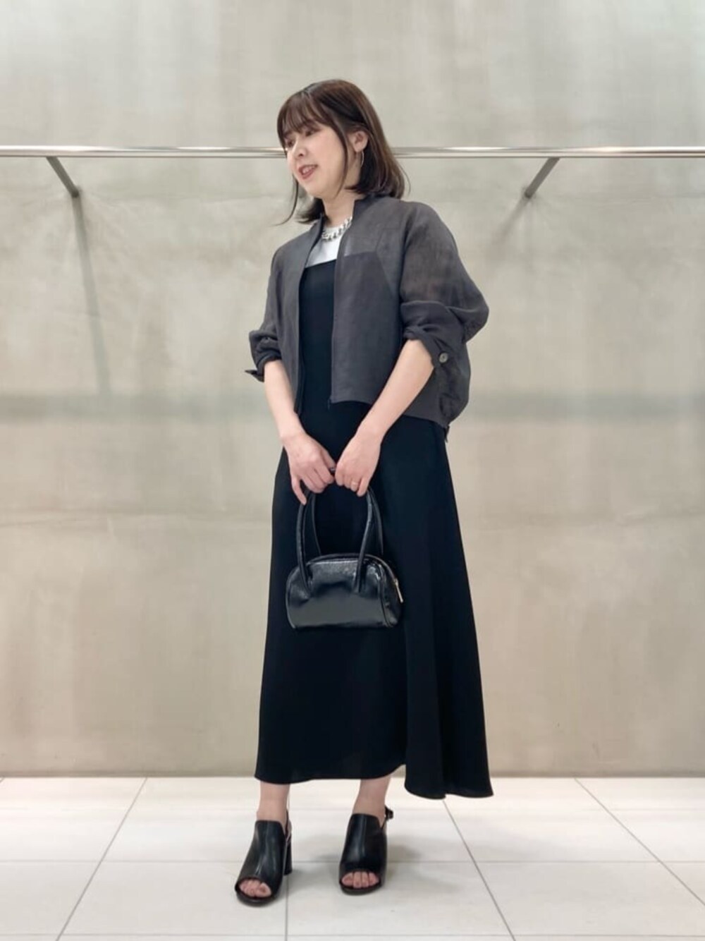 ブラック系のサンダル、ブラック系のワンピース、シルバー系のネックレスを着用したレディースの夏コーディネートの1枚目の写真