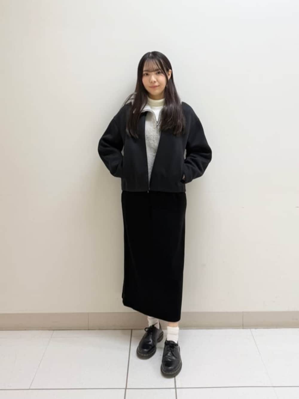 ベージュ系のパーカー、ブラック系のスカート、ブラック系のブルゾンを着用したレディースの冬コーディネートの1枚目の写真