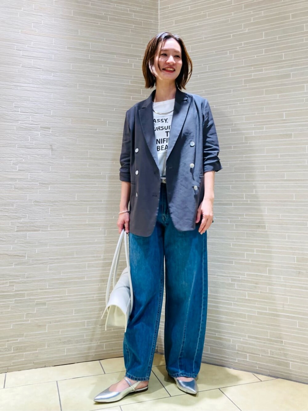 ホワイト系のTシャツ/カットソー、グレー系のテーラードジャケット、ブルー系のデニムパンツを着用したレディースの春コーディネートの1枚目の写真