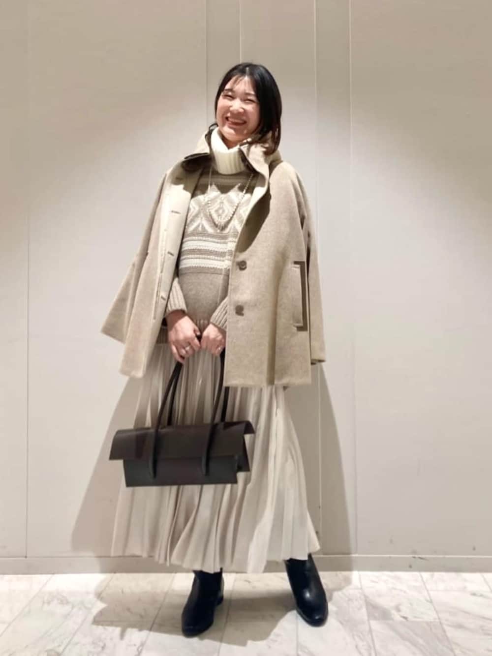 ホワイト系のスカート、ブラウン系のその他アウター、ベージュ系のニット/セーターを着用したレディースの冬コーディネートの1枚目の写真