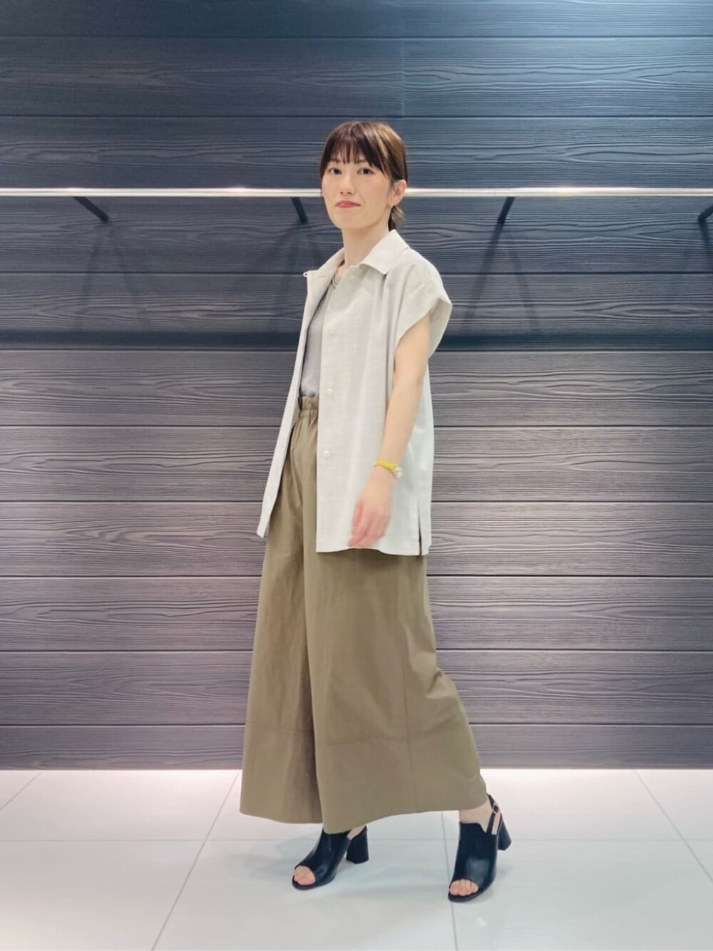 ブラック系のサンダル、イエロー系のその他パンツ、ホワイト系のベストを着用したレディースの夏コーディネートの1枚目の写真