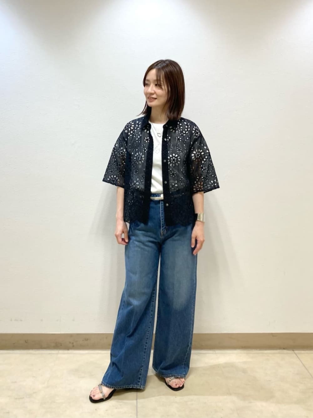 ブルー系のデニムパンツ、ブラック系のシャツ/ブラウス、グレー系のサンダルを着用したレディースの春コーディネートの1枚目の写真