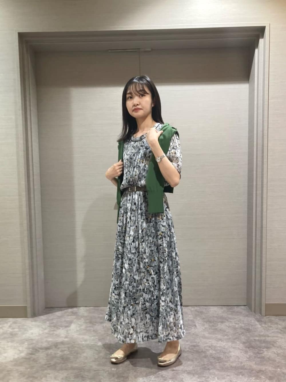 ブラック系のワンピース、グリーン系のニット/セーター、ブラック系のベルトを着用したレディースの夏コーディネートの1枚目の写真