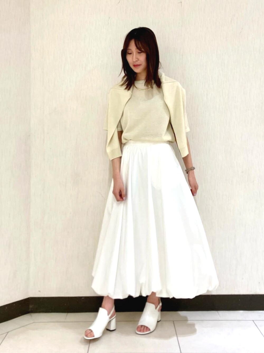 ホワイト系のスカート、イエロー系のカーディガン/ボレロ、イエロー系のニット/セーターを着用したレディースの春コーディネートの1枚目の写真