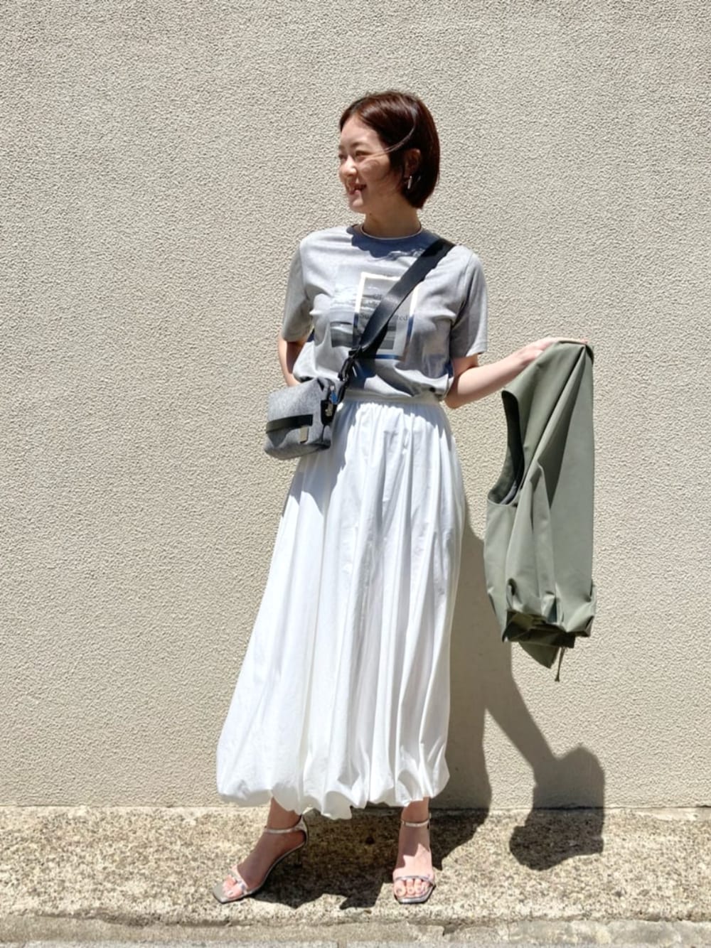 ホワイト系のスカート、ベージュ系のTシャツ/カットソーを着用したレディースの夏コーディネートの1枚目の写真