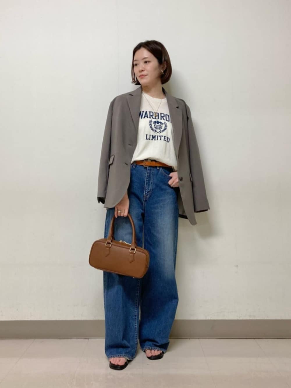 ブラウン系のボストンバッグ、ブルー系のデニムパンツ、ホワイト系のニット/セーターを着用したレディースの春コーディネートの1枚目の写真