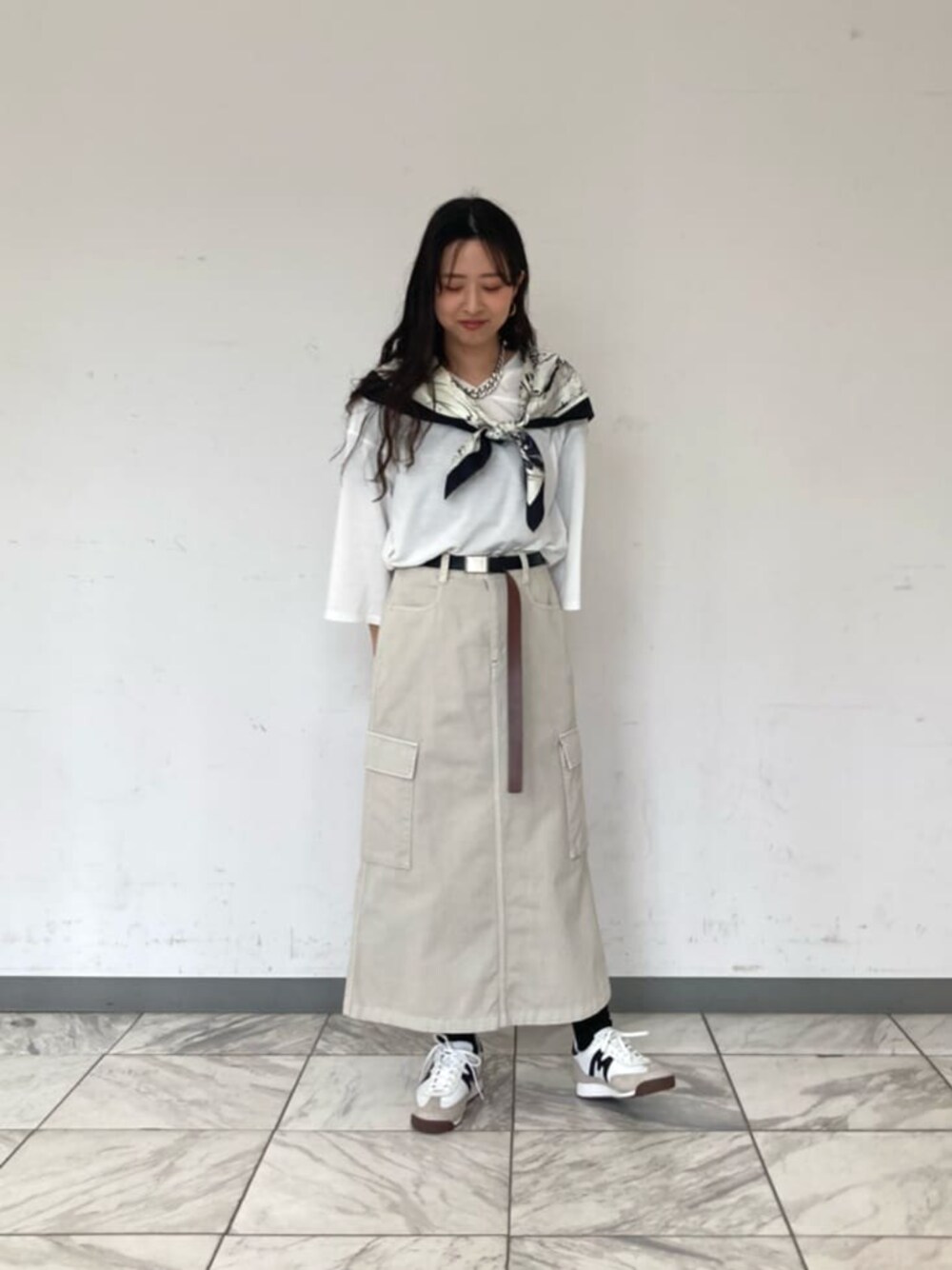 ホワイト系のTシャツ/カットソー、ベージュ系のスカート、ブラック系のストール/ショールを着用したレディースの春コーディネートの1枚目の写真