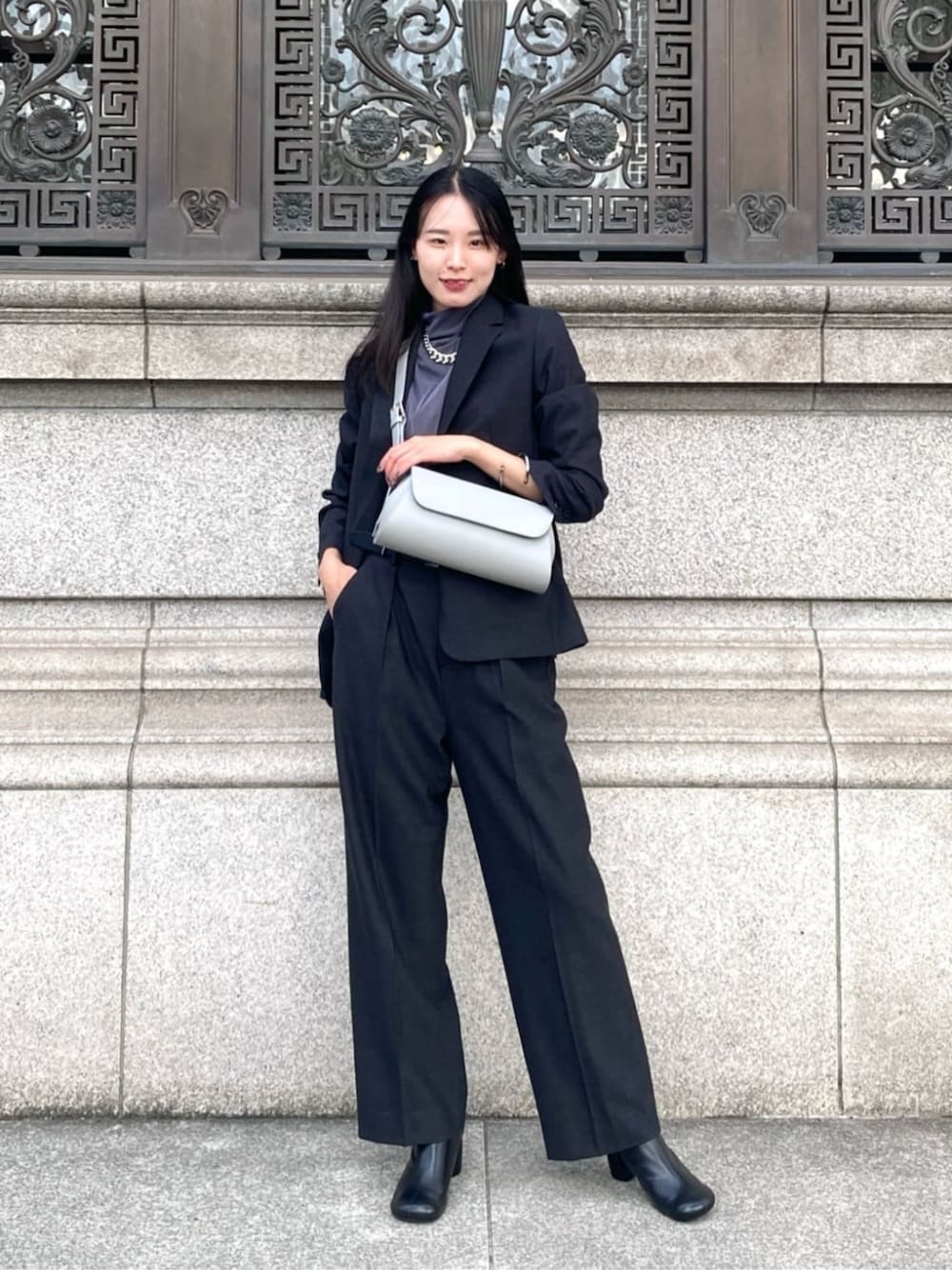 グレー系のスーツジャケット、グレー系のスーツパンツ、グレー系のショルダーバッグを着用したレディースの秋コーディネートの1枚目の写真