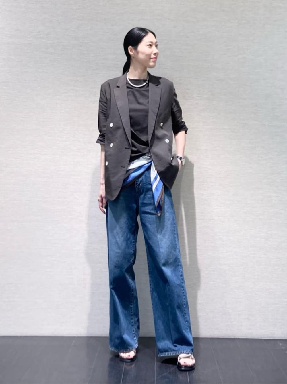 ブルー系のデニムパンツ、グレー系のテーラードジャケット、グレー系のサンダルを着用したレディースの夏コーディネートの1枚目の写真