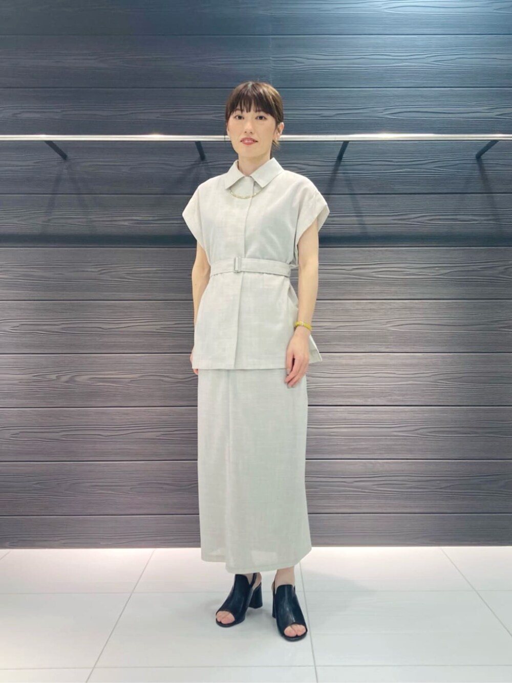 ブラック系のサンダル、ホワイト系のスカート、ホワイト系のベストを着用したレディースの夏コーディネートの1枚目の写真