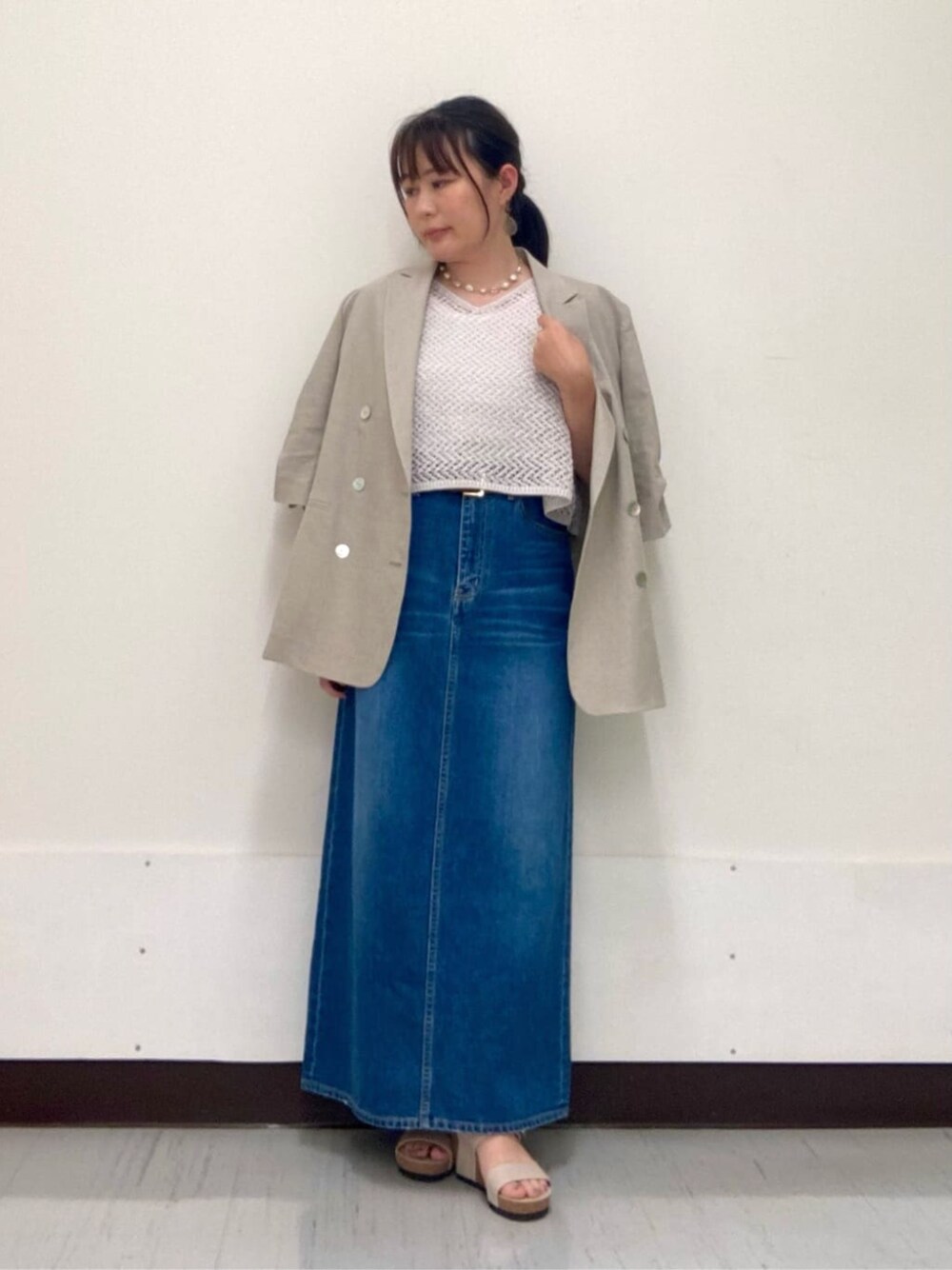 グレー系のスカート、ベージュ系のテーラードジャケット、グレー系のアンサンブルを着用したレディースの夏コーディネートの1枚目の写真