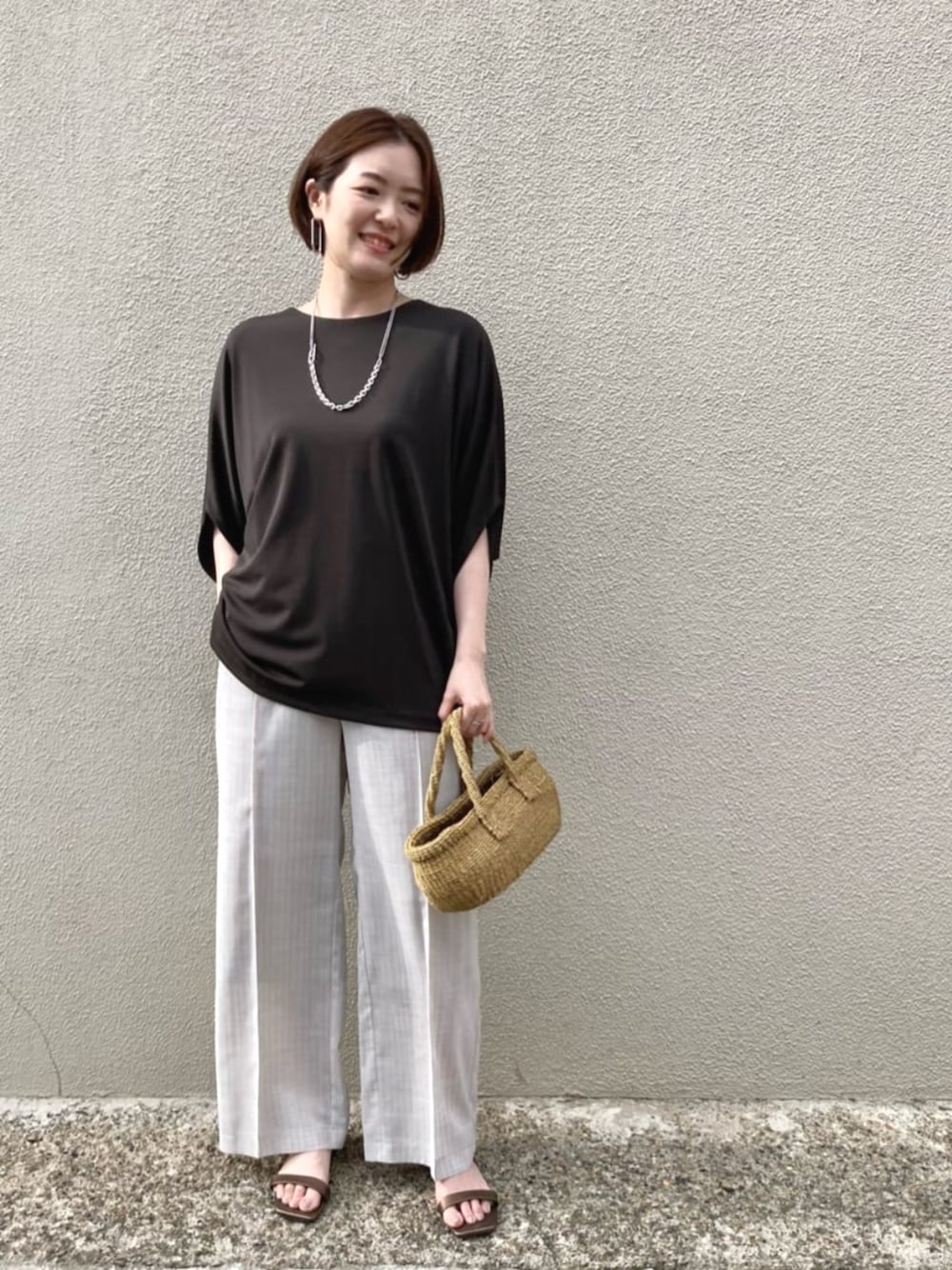 ホワイト系のスラックス、シルバー系のネックレスを着用したレディースの夏コーディネートの1枚目の写真