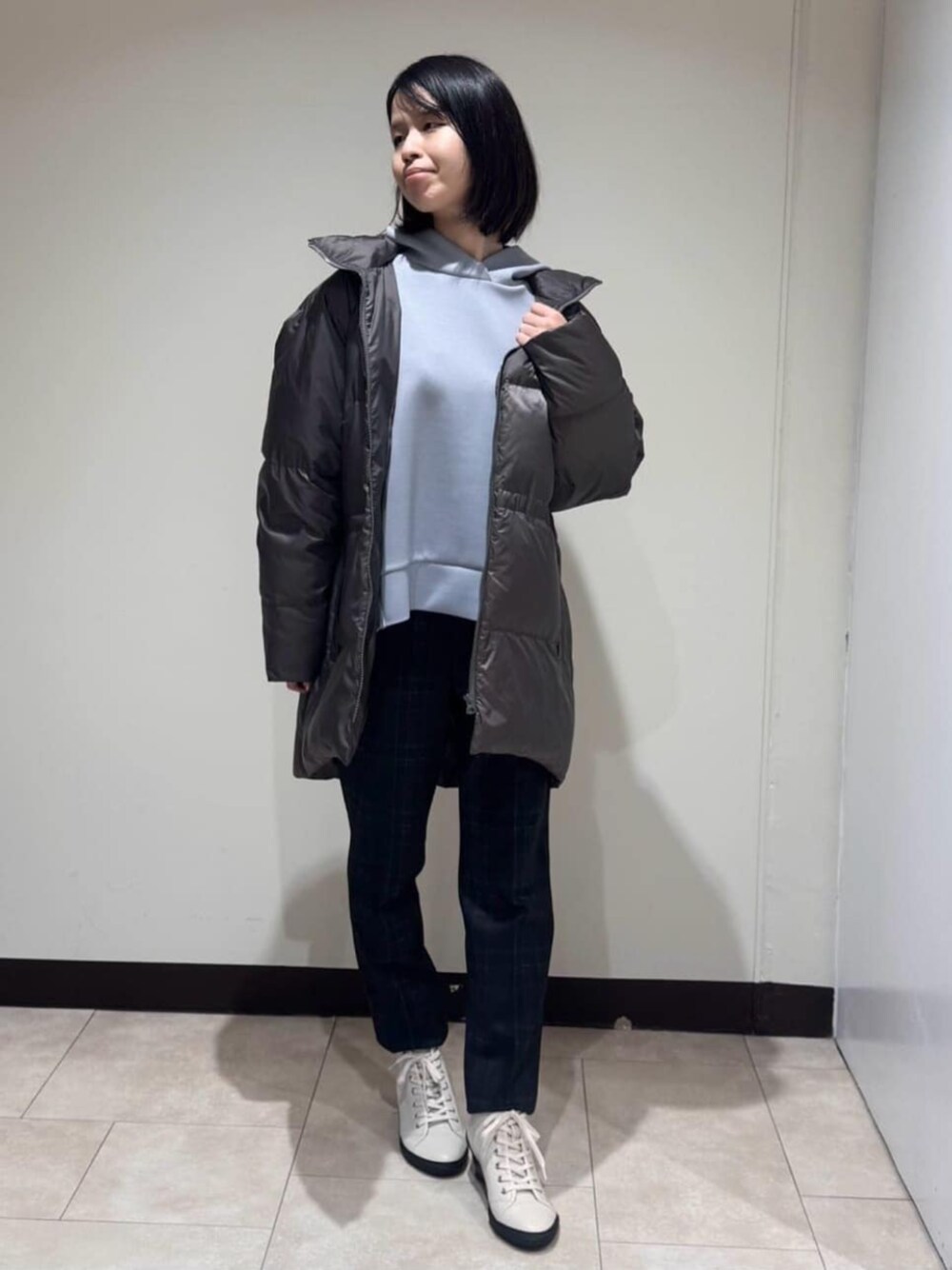 グレー系のダウンジャケット/コート、ブラウン系のその他パンツ、ブルー系のパーカーを着用したレディースの冬コーディネートの1枚目の写真