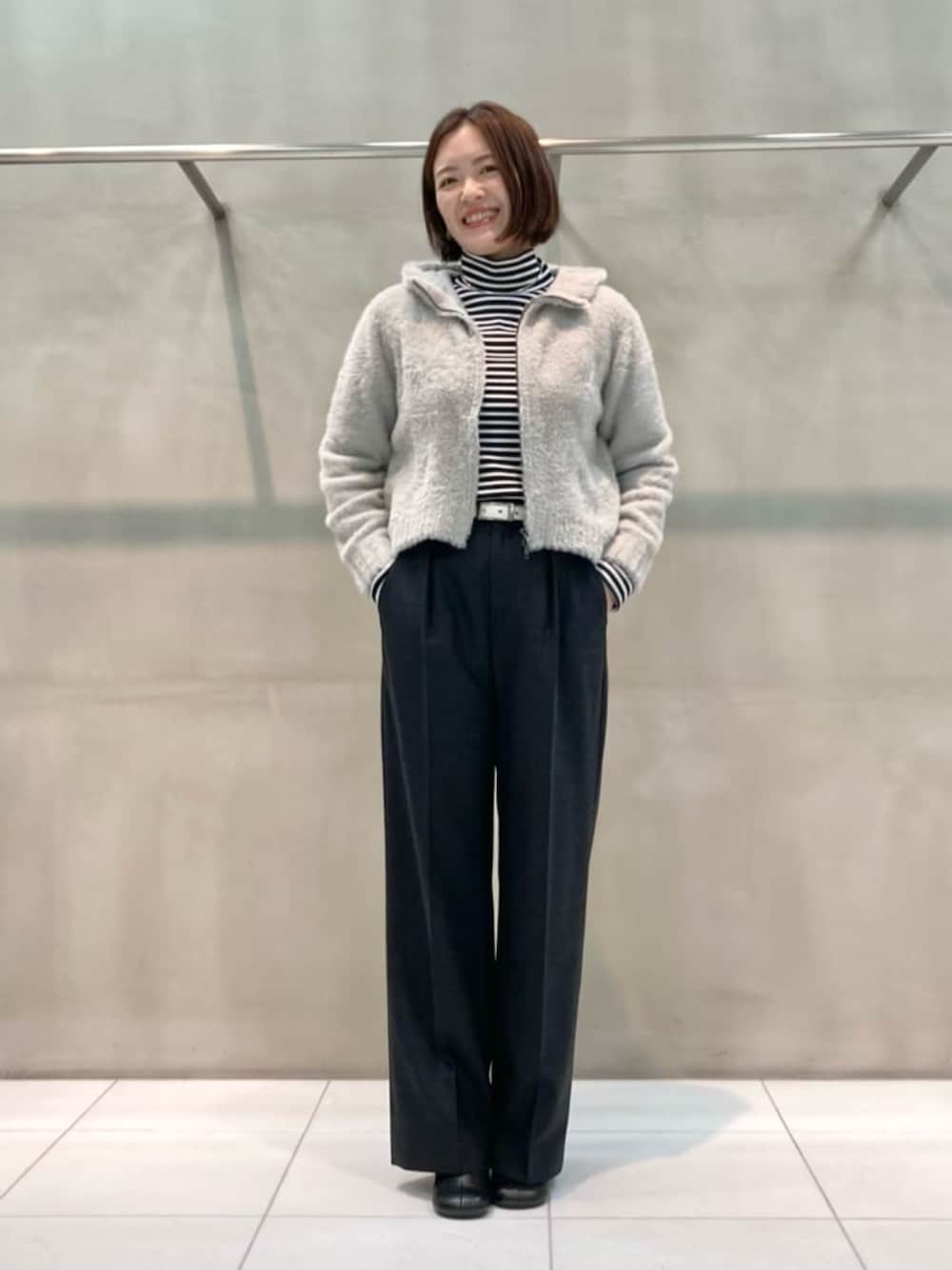グレー系のスーツパンツ、ブラック系のブーツ、ベージュ系のパーカーを着用したレディースの秋コーディネートの1枚目の写真