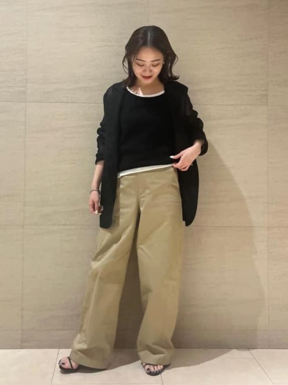 イエロー系のチノパンツ、ブラック系のタンクトップを着用したレディースの夏コーディネートの1枚目の写真