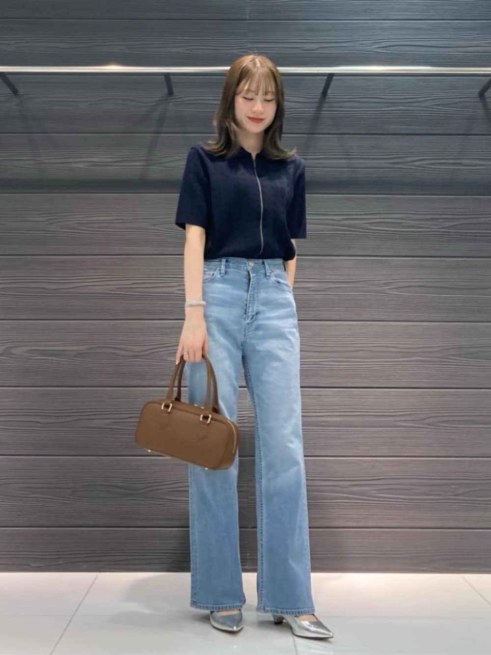 ブルー系のデニムパンツ、ブルー系のカーディガン/ボレロ、ブラウン系のボストンバッグを着用したレディースの春コーディネートの1枚目の写真