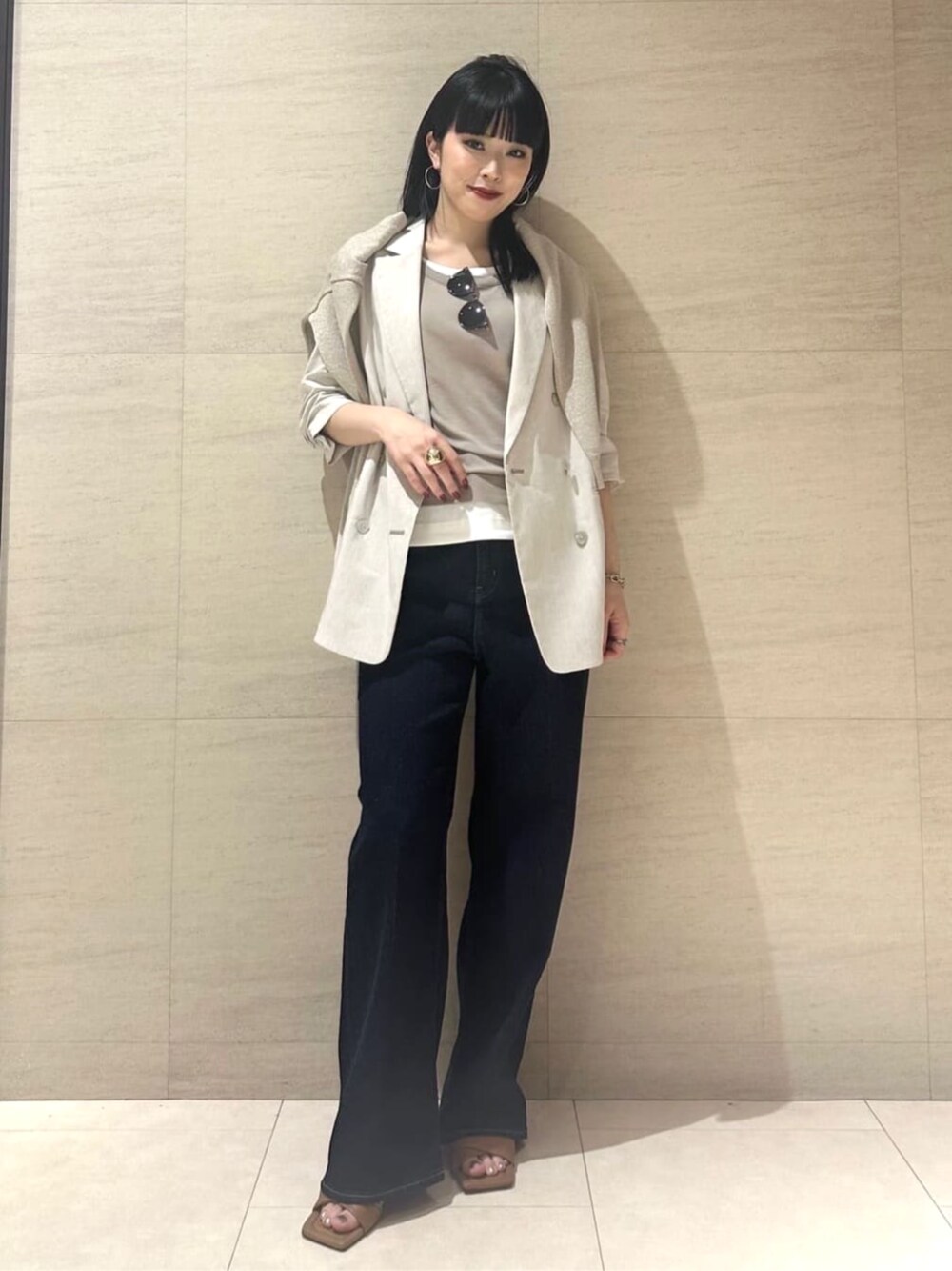 ブルー系のデニムパンツ、ベージュ系のテーラードジャケット、ベージュ系のタンクトップを着用したレディースの夏コーディネートの1枚目の写真