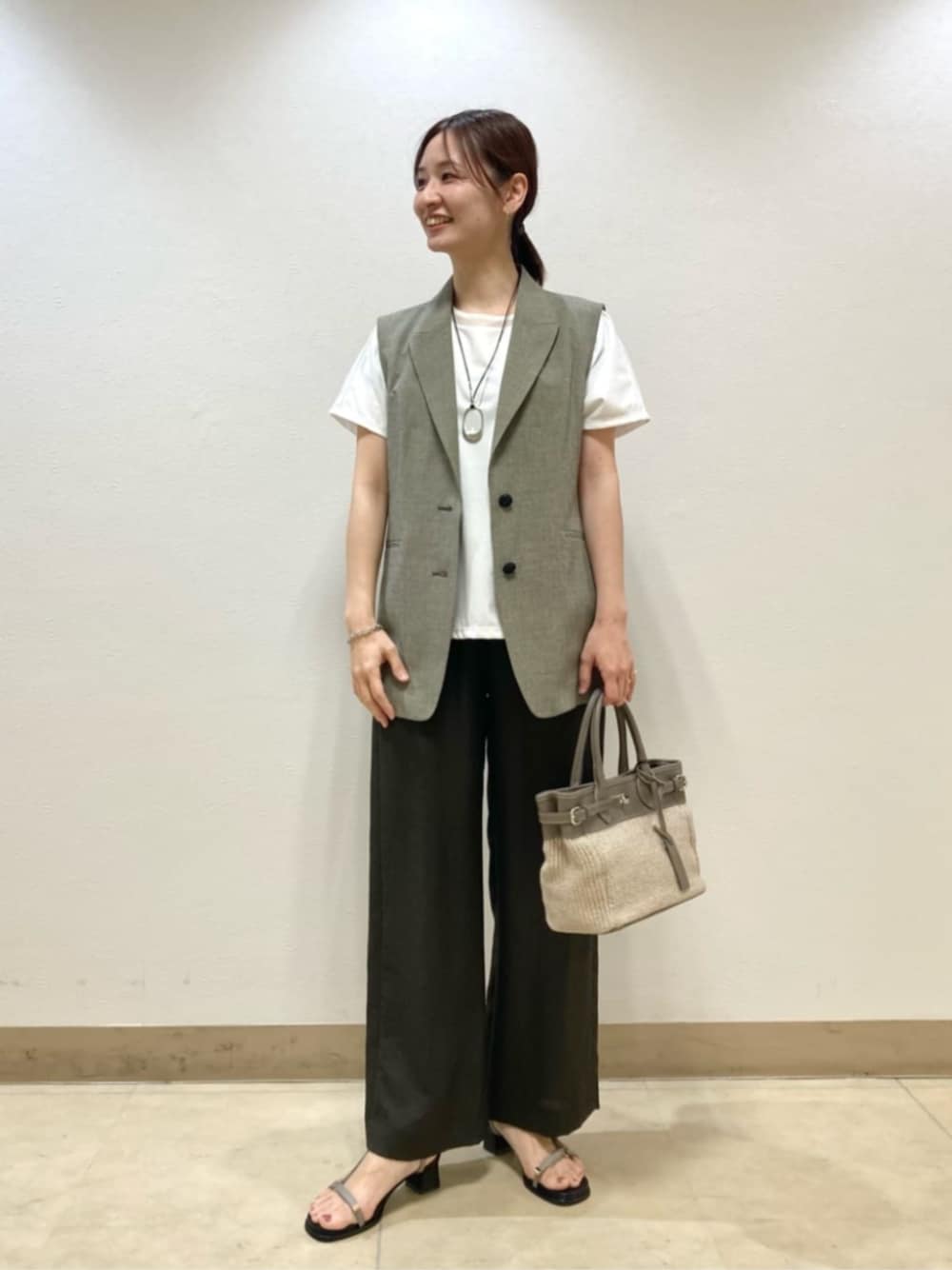ベージュ系のベスト、ブラウン系のその他パンツ、ホワイト系のTシャツ/カットソーを着用したレディースの春コーディネートの1枚目の写真