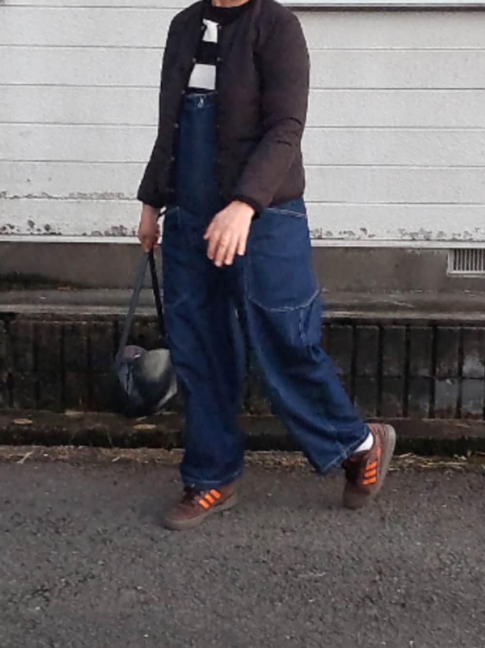 ブラック系のノーカラージャケット、ブラウン系のスニーカー、ブラック系のつなぎ/オールインワンを着用したレディースの冬コーディネートの1枚目の写真