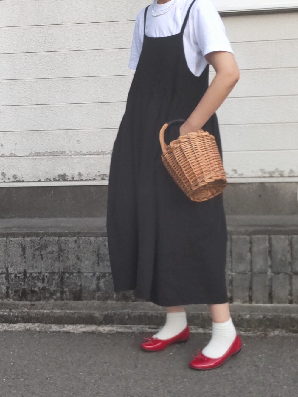 ブラック系のワンピース、ブラウン系のかごバッグ、シルバー系のネックレスを着用したレディースの夏コーディネートの1枚目の写真