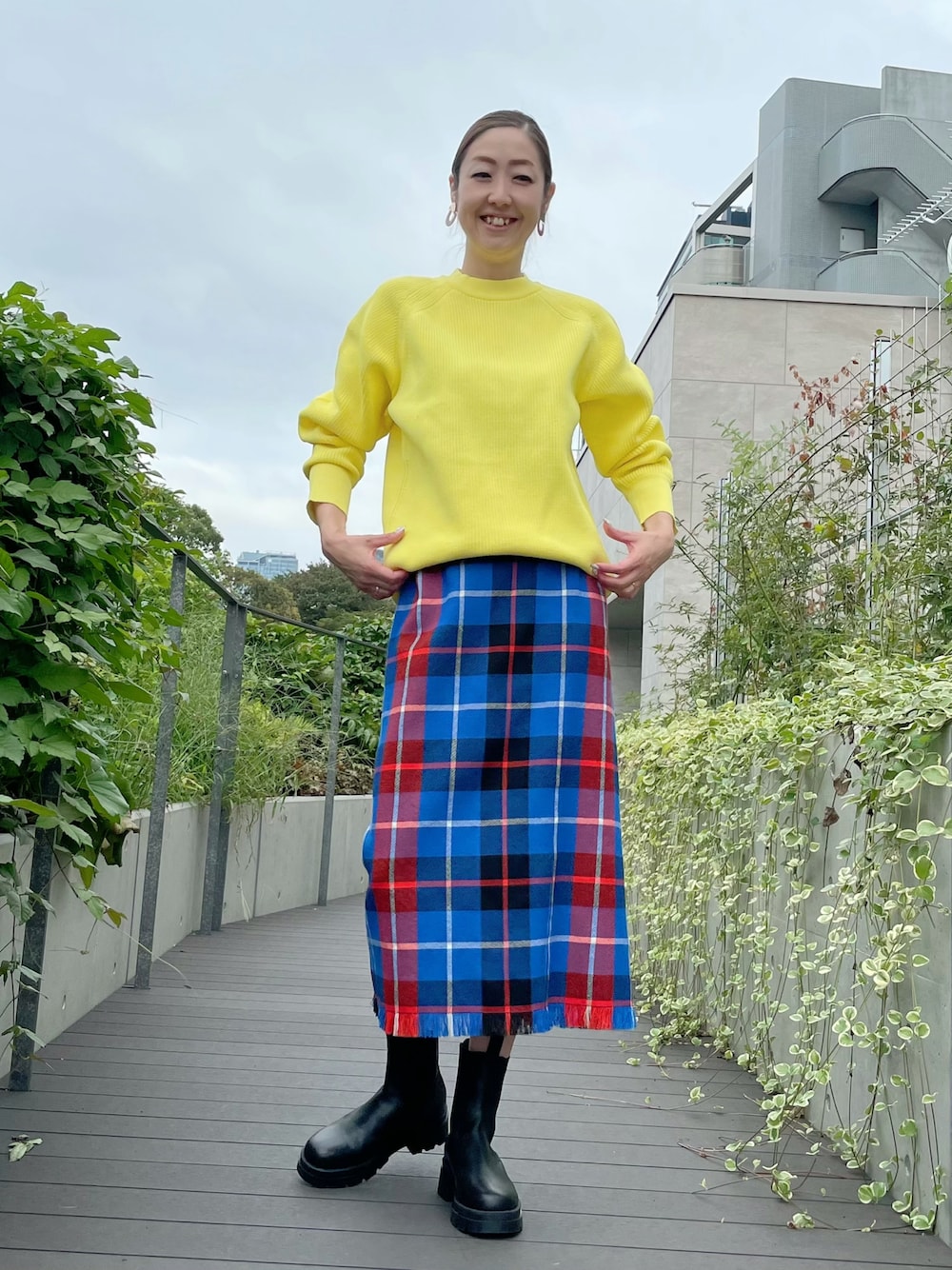 イエロー系のニット/セーター、ブルー系のスカート、ブルー系のスカートを着用したレディースの秋コーディネートの1枚目の写真