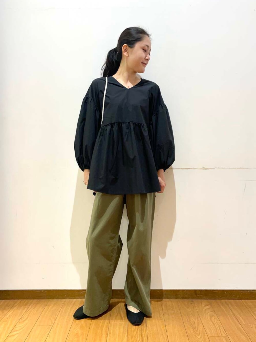 ホワイト系のショルダーバッグ、ブラック系のシャツ/ブラウス、グリーン系のチノパンツを着用したレディースの夏コーディネートの1枚目の写真