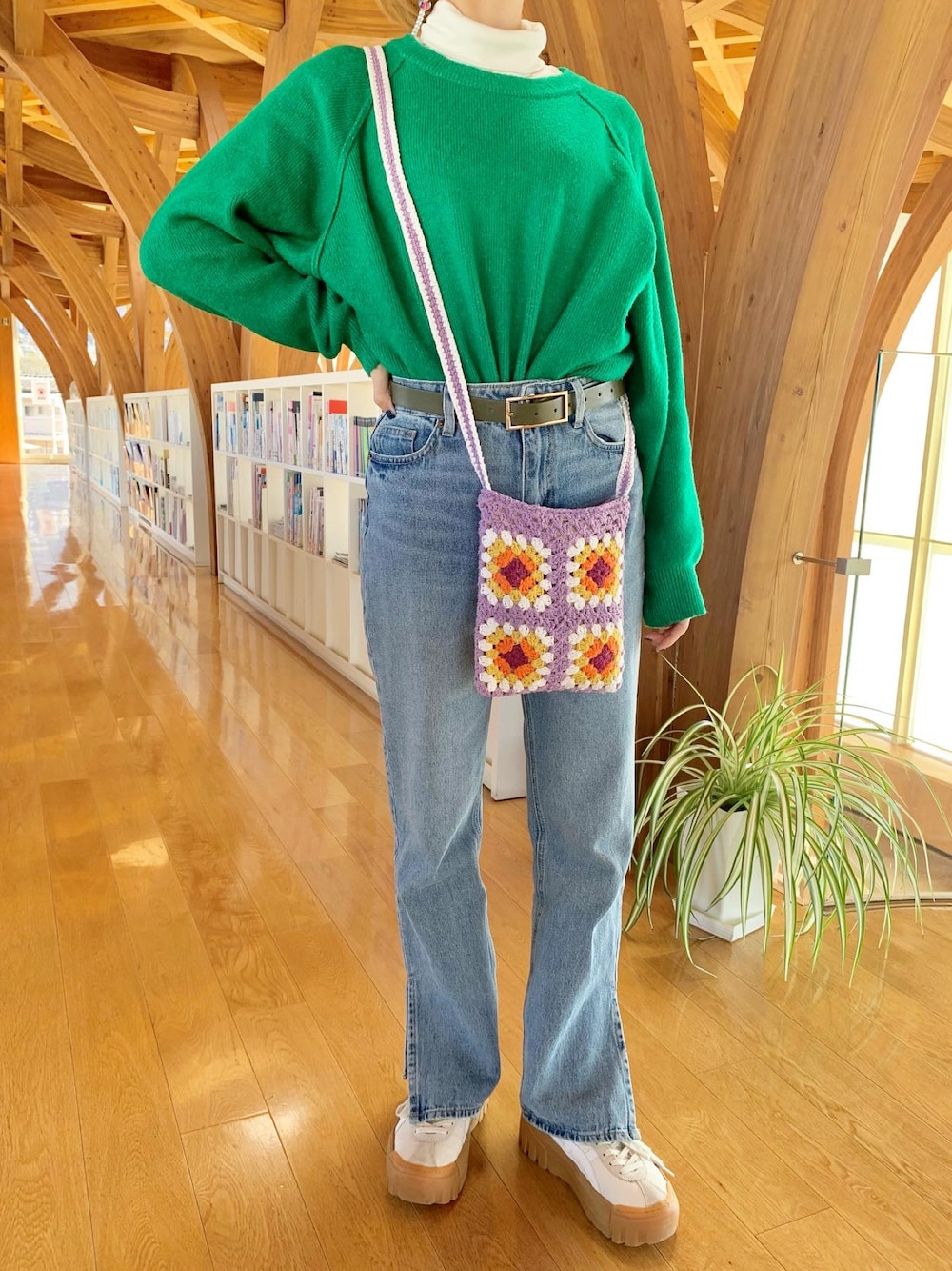 ホワイト系のスニーカー、ブルー系のデニムパンツ、パープル系のショルダーバッグを着用したレディースの冬コーディネートの1枚目の写真