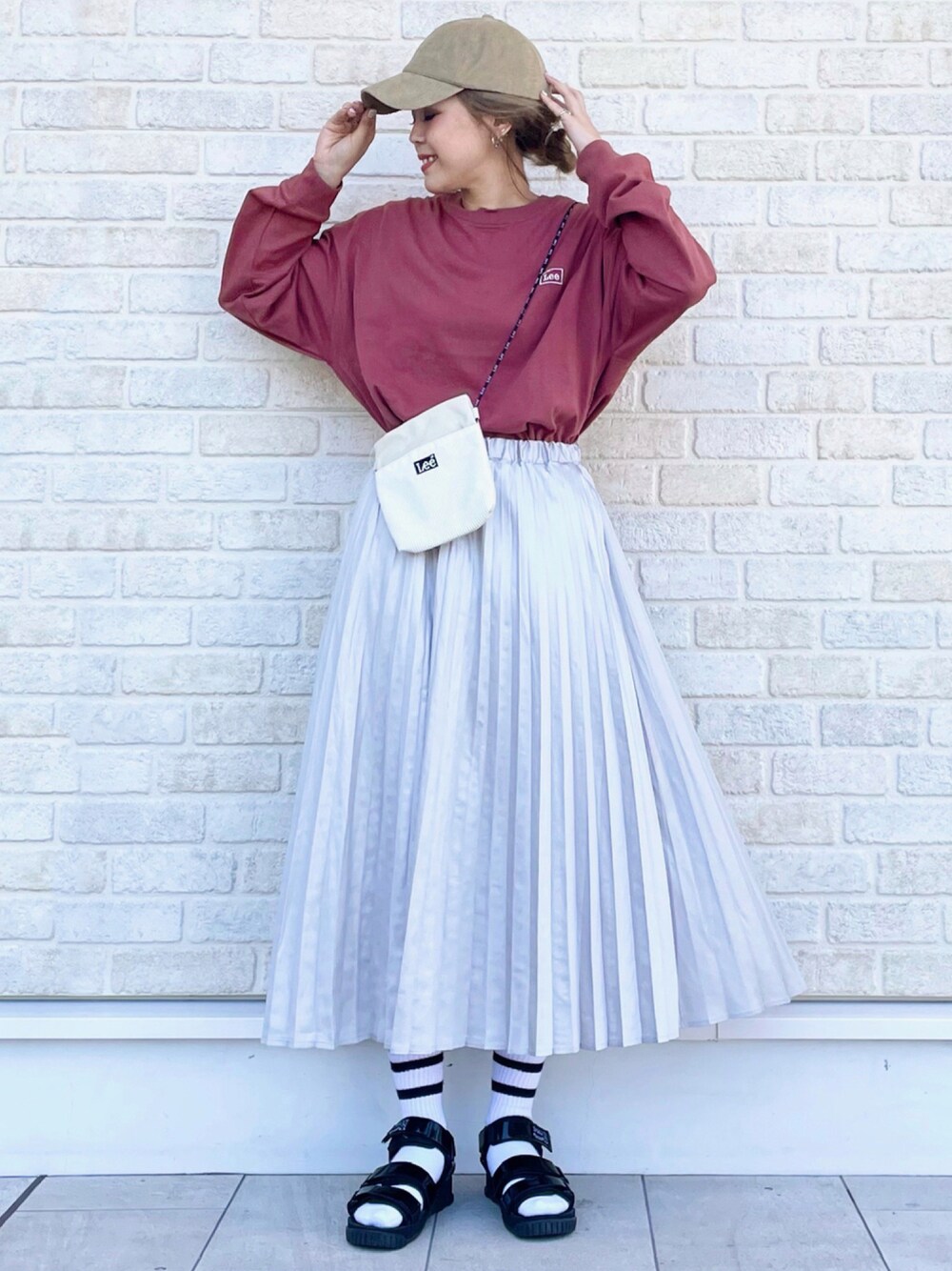 レッド系のTシャツ/カットソー、ホワイト系のショルダーバッグ、ベージュ系のスカートを着用したレディースの秋コーディネートの1枚目の写真