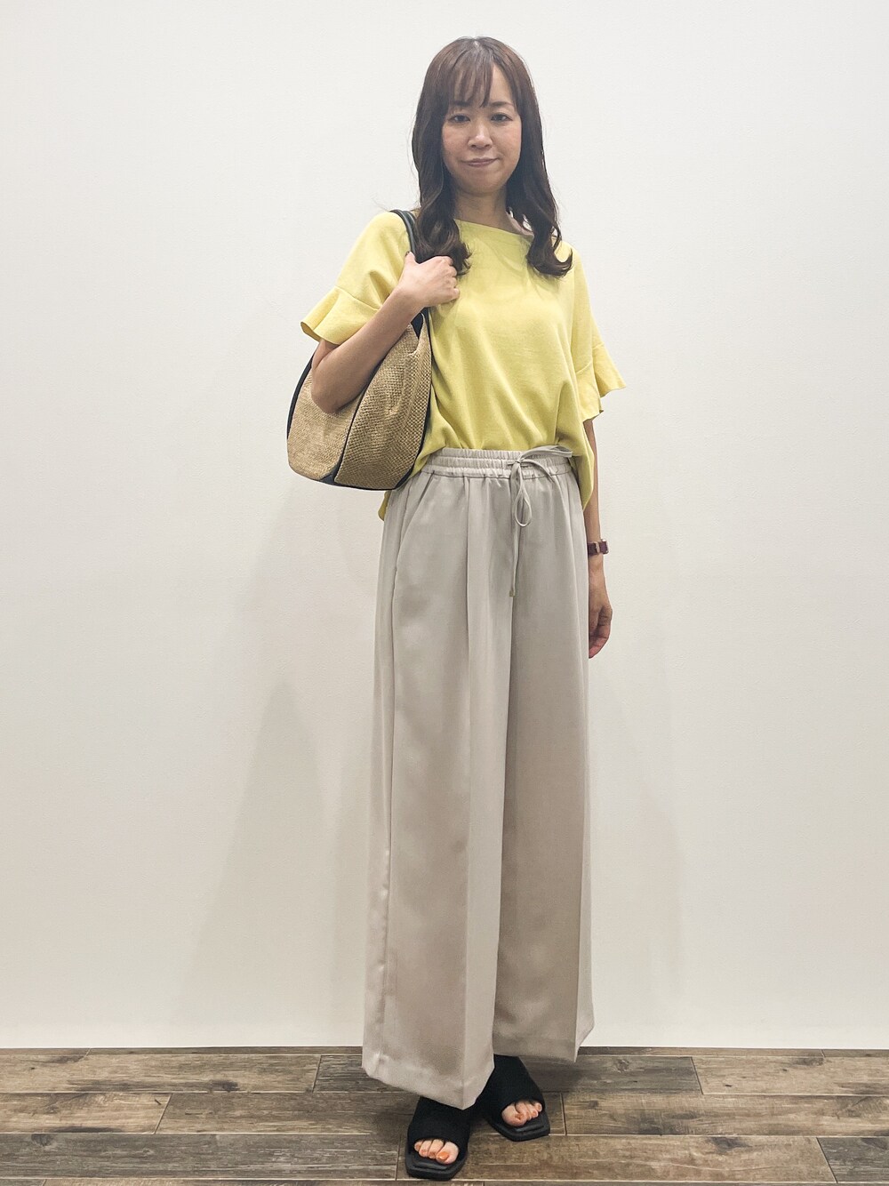 イエロー系のニット/セーター、ベージュ系のその他パンツ、ベージュ系のトートバッグを着用したレディースの春コーディネートの1枚目の写真