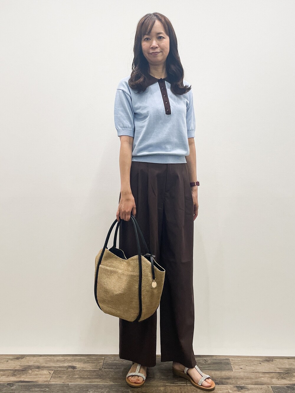 ブルー系のニット/セーター、ブラウン系のその他パンツ、ベージュ系のトートバッグを着用したレディースの春コーディネートの1枚目の写真