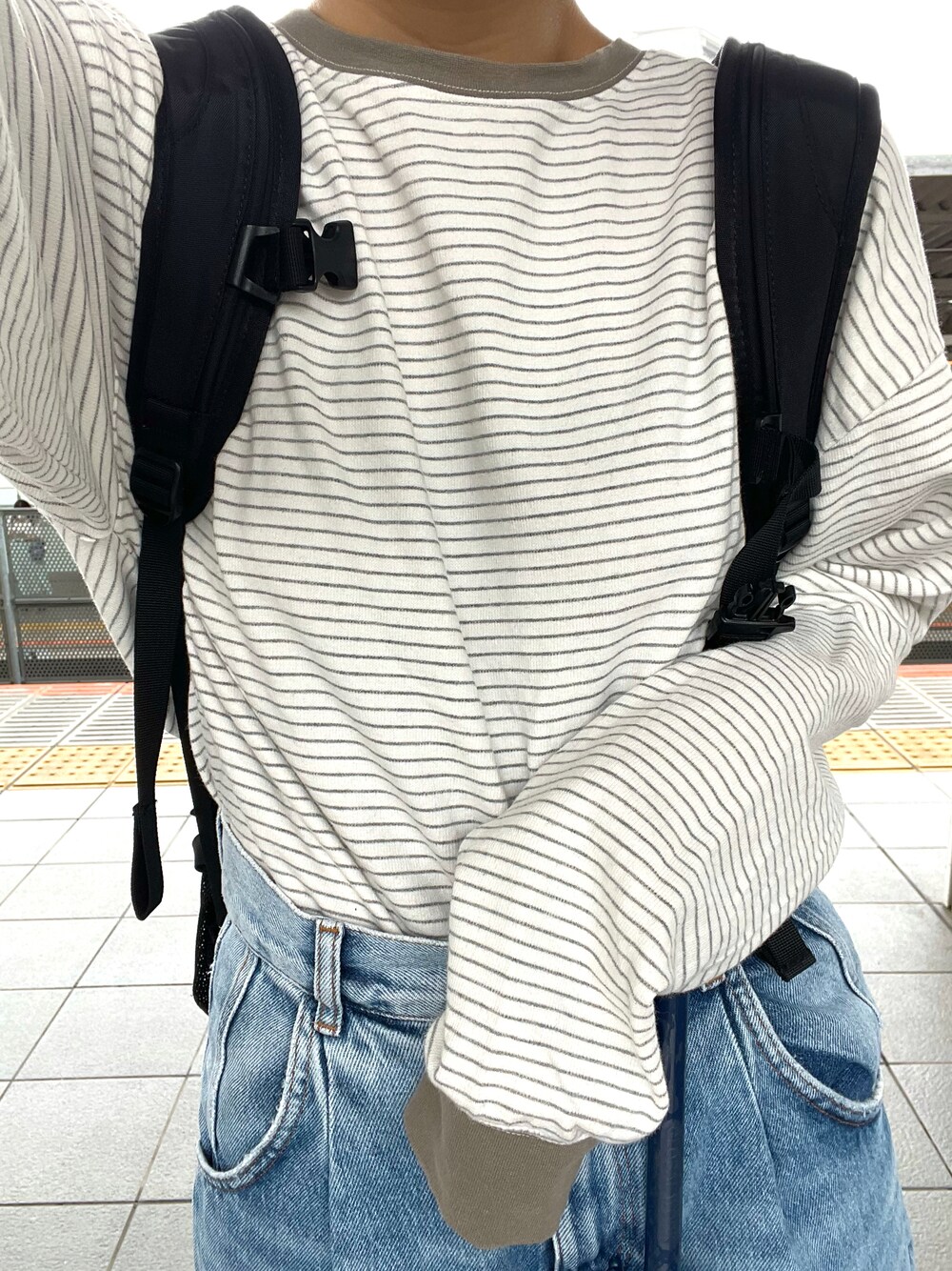 グリーン系のTシャツ/カットソー、ブルー系のデニムパンツ、ブラック系のバックパック/リュックを着用したレディースの秋コーディネートの1枚目の写真